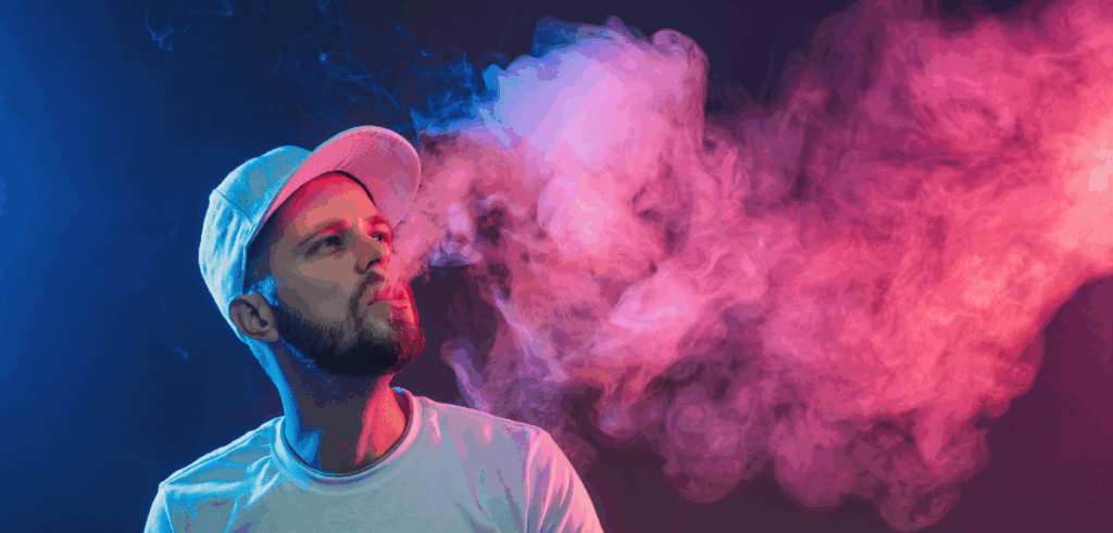 Man exhales a cloud of vapor under moody blue and pink lighting, creating a dramatic effect.