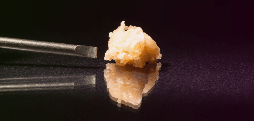Close up of a cannabis concentrate next to a concentrate poker tool.
