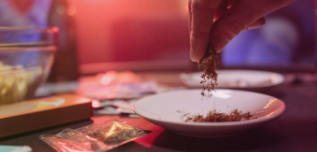 A close-up image of someone sprinkling ground cannabis flower into a shallow dish.