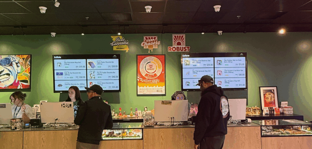 Two male customers wearing black t-shirts checkout at the sales counter at Stairway Cannabis.