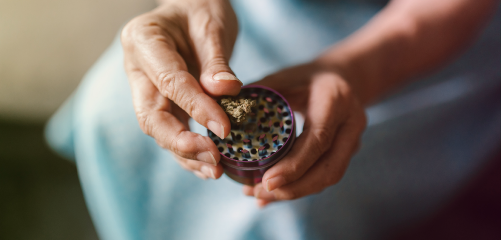 Close-up view of a middle-aged woman holding a cannabis flower grinder with a nug on top of the grinder.