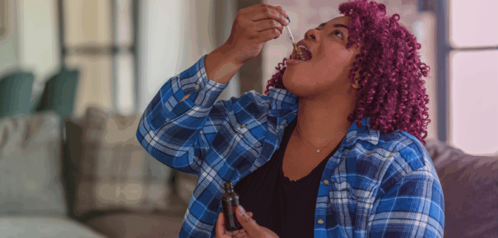 A woman uses a tincture dropper, placing a dose under her tongue to support better sleep.